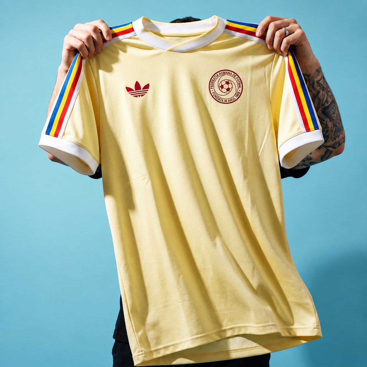 Romania 1986 yellow retro home jersey held up against a teal background.