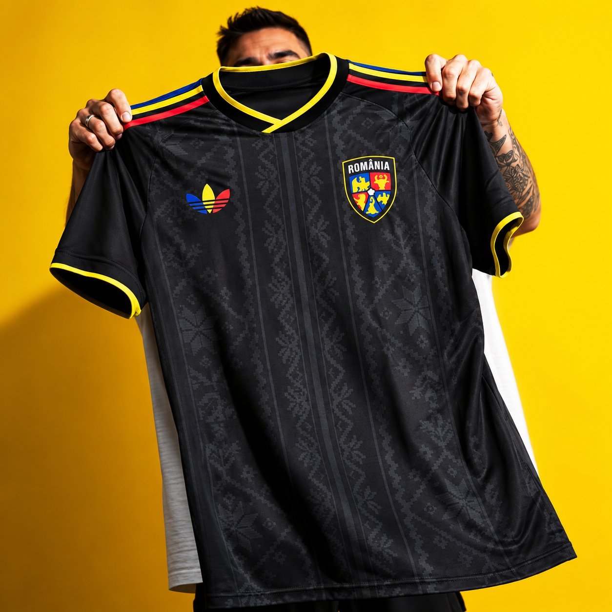 Romania retro away jersey in black with subtle pattern, held up against a yellow background.