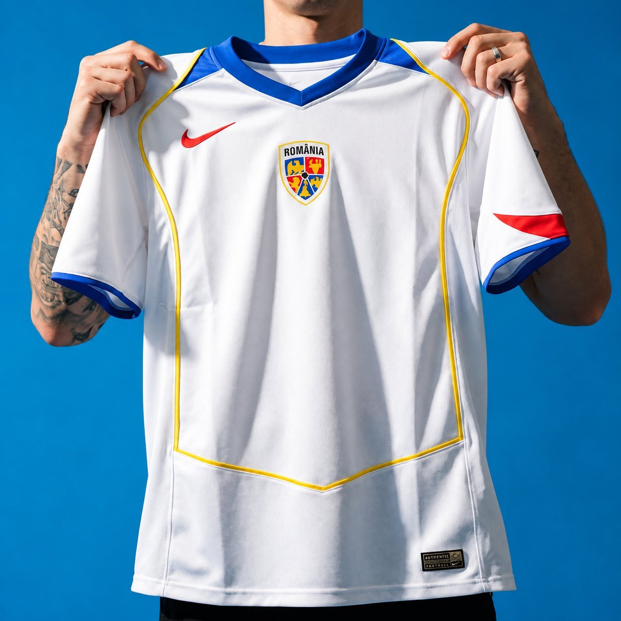 Romania retro home jersey in white with blue and yellow trim, held up against a blue background.